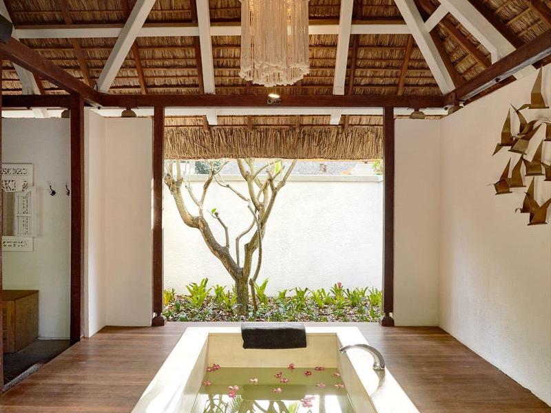 Moderní dvůr s vodní plochou, dřevěnou podlahou a dekorativním lustrem pod otevřenou střechou.