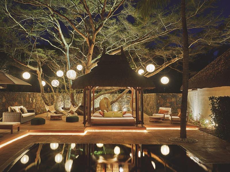 Noční venkovní lounge s pohodlným posezením a osvětlením u hotelového bazénu.