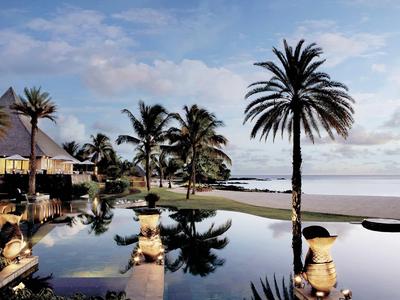 Tropischer Strand mit Palmen, einem ruhigen Pool und einem geschmackvoll beleuchteten Restaurant bei Sonnenuntergang.