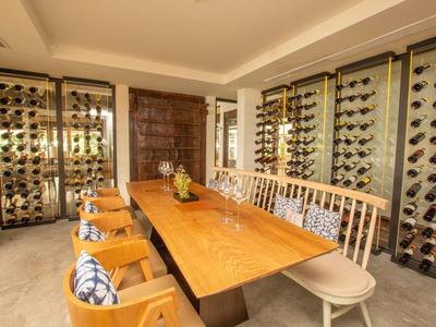 Esszimmer mit langem Holztisch, verschiedenen Stühlen und großen Weinregalen an den Wänden.