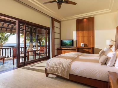 Schlafzimmer mit Doppelbett, Holzdekor, TV, Balkon und Blick aufs Meer bei Tageslicht.