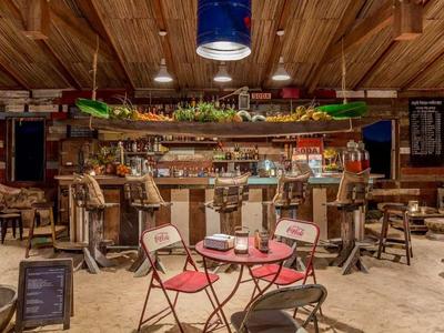 Rustikale Bar mit Holzmöbeln, roten Stühlen, Theke und gemütlicher Beleuchtung im Holzraum.