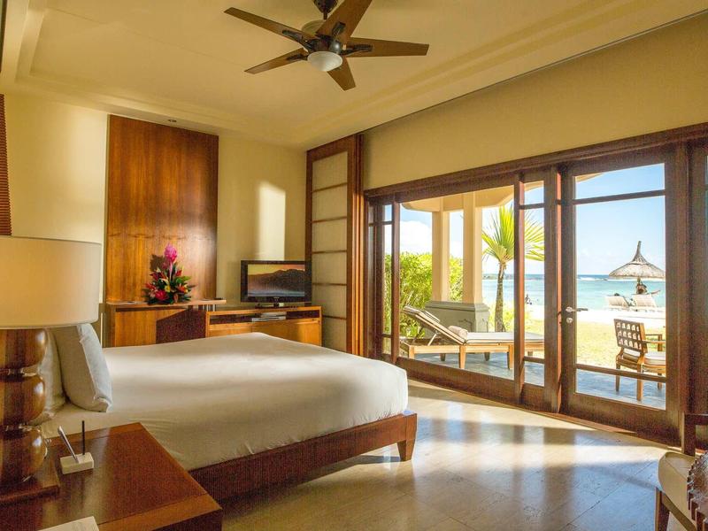 Helles, modernes Schlafzimmer mit großem Bett, Deckenventilator und Blick auf Terrasse und Meer.