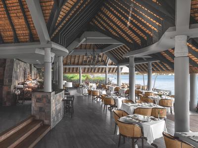 Amplio restaurante con techo de madera, columnas y mesas preparadas con vistas al agua.