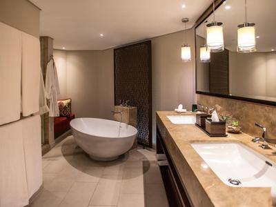 Elegante baño con bañera independiente, lavabos dobles y luz cálida.