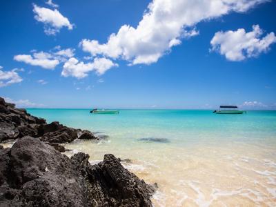 Mare turchese limpido con rocce in primo piano e cielo nuvoloso