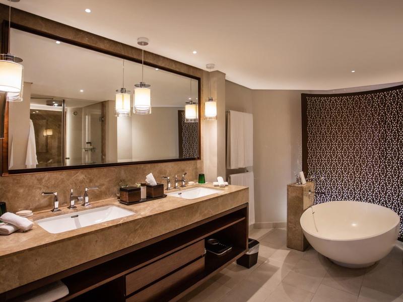 Baño elegante con lavabo doble, espejo grande y bañera independiente.