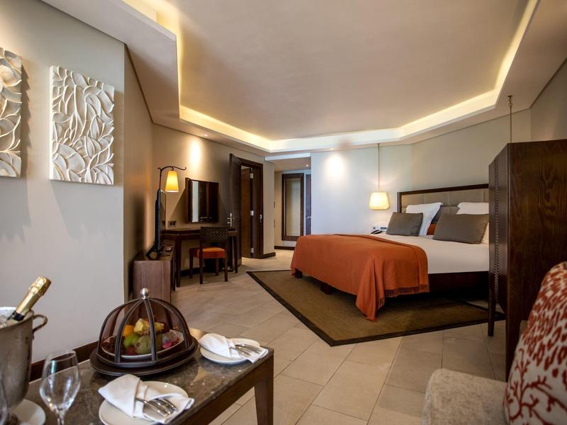 Acogedora habitación de hotel con cama grande, colores cálidos y paneles decorativos en la pared.