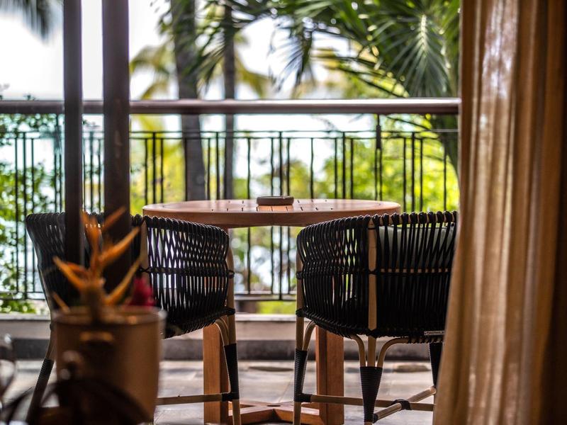 Área de terraza con mesa y sillas, rodeada de vegetación y vista al agua.