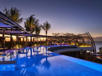 Abendlicher Infinity-Pool mit Palmen und Meerblick an einem Hotelresort.