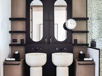 Modernes Badezimmer mit zwei weißen Standwaschbecken vor schwarzem Doppelspiegel und Holzregalen.