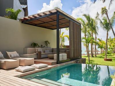 Moderner Außenbereich mit Pool, Lounge-Sitzbereichen und Palmen im Hintergrund bei Sonnenschein.