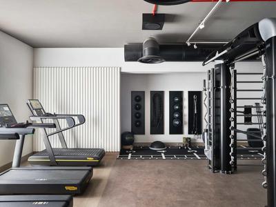 Moderner Fitnessraum mit Laufbändern, Gewichten und multifunktionalen Trainingsgeräten.