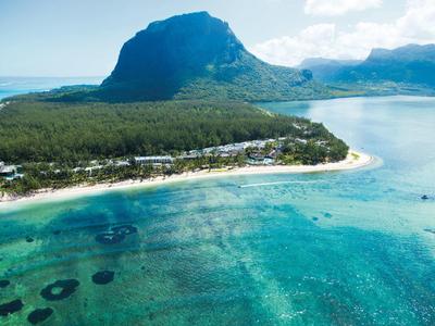 Türkisfarbenes Meer mit Sandstrand und bewaldetem Berghang im Hintergrund