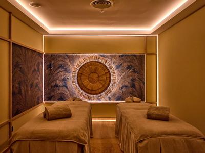 Behandlungsraum mit zwei Massageliegen und gedämpfter Beleuchtung in einem Hotel-Spa.