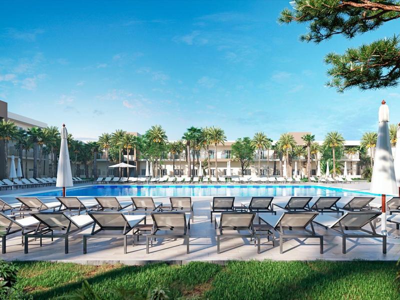 Moderner Hotelpool mit Liegestühlen und Blick auf Palmen unter blauem Himmel.