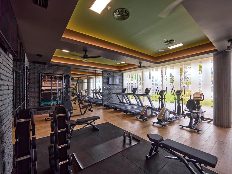 Moderner Fitnessraum mit Cardio- und Kraftgeräten, hellem Boden und großen Fenstern