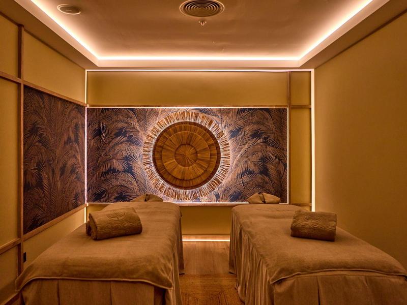 Behandlungsraum mit zwei Massageliegen und gedämpfter Beleuchtung in einem Hotel-Spa.