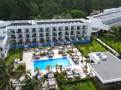 Complesso alberghiero moderno con piscina, lettini e ambientazione verde in una giornata di sole.