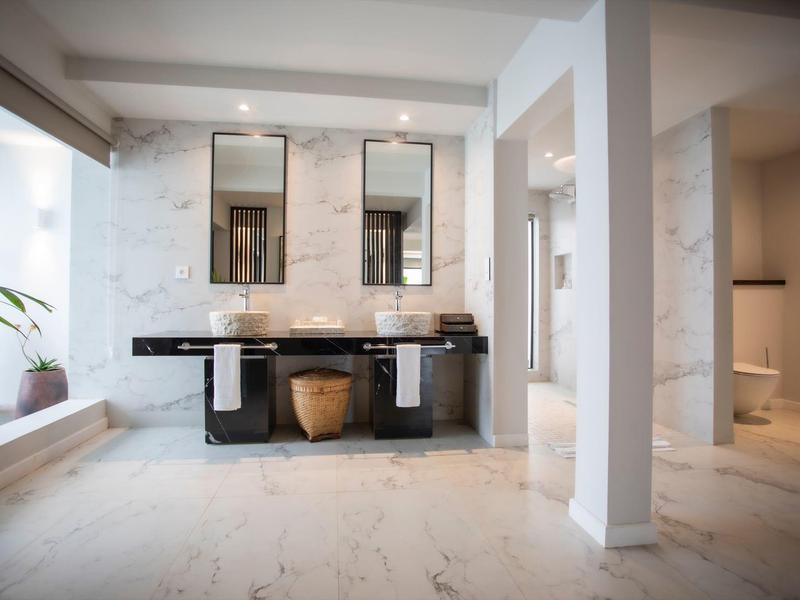 Großes Badezimmer mit weißem Marmorboden, Doppelwaschbecken und zwei Spiegeln an der Wand.