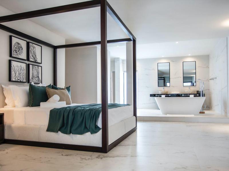 Modernes Hotelzimmer mit Himmelbett und freistehender Badewanne in hell gestaltetem Raum.