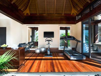 Coin fitness moderne dans un hôtel avec sol en bois et vue sur la verdure.