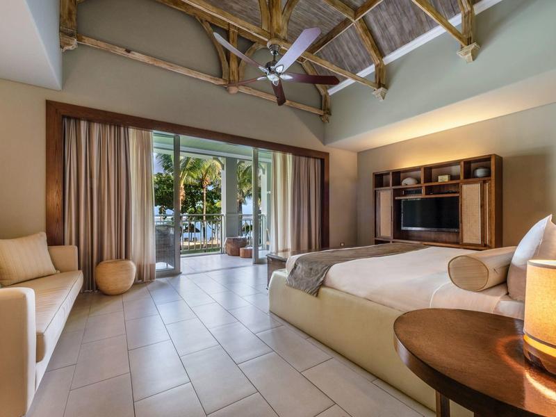 Cozy hotel room with large sliding doors opening to a terrace and tropical view.