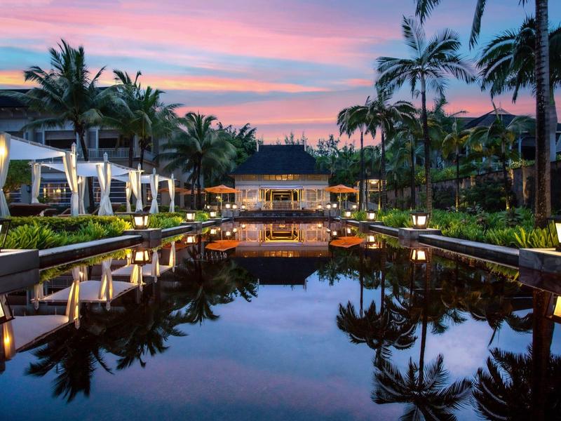 Luxurious resort with pool and palm trees at sunset