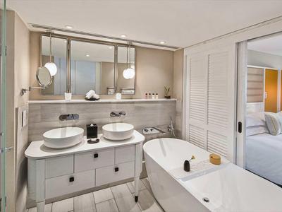Modern bathroom with double sinks, freestanding bathtub, and access to the bedroom.