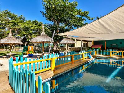A colorful playground with water pools, surrounded by fences and large sunshades.