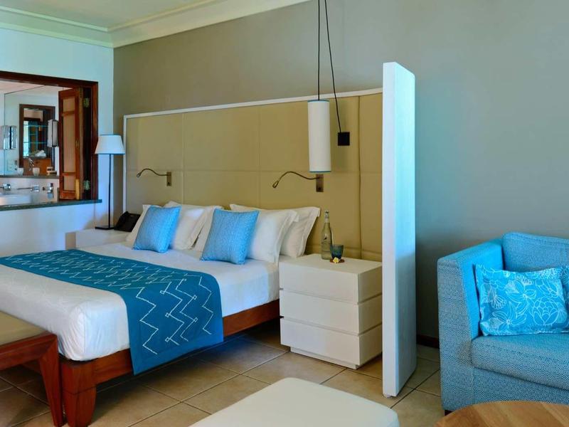 Modern hotel room with double bed, blue accents, and a comfortable sofa.