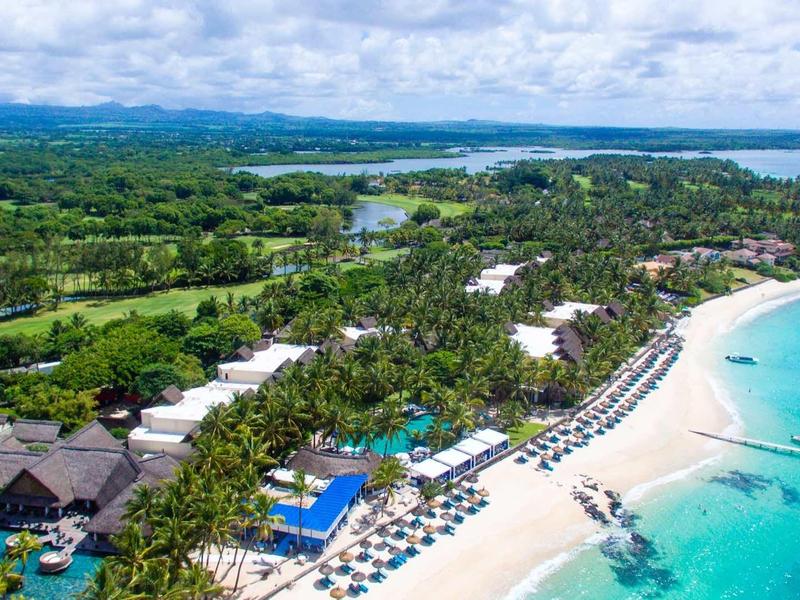 Aerial view of a tropical resort with beach, sun loungers, and turquoise sea.