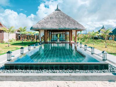 Infinity bazén s chatrčí střechou a posezením v tropickém resortu.