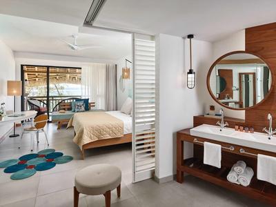 Moderní hotelový pokoj s postelí, psacím stolem, koupelnou a balkonem s výhledem.