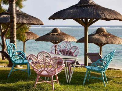 Bunte Sitzmöbel unter Strohdächern mit Blick auf das Meer bei Sonnenuntergang.