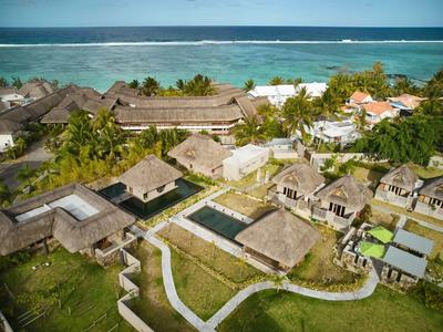 Vista aerea di un resort tropicale sul mare con bungalow e sentieri ben curati.