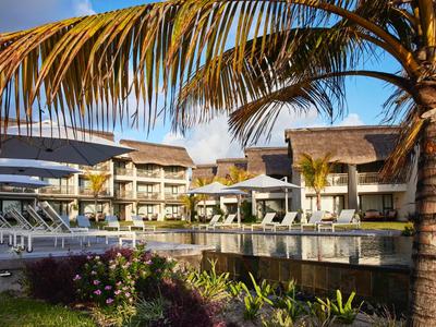 Moderner Hotelkomplex mit Pool, Liegestühlen und Palmen bei sonnigem Himmel