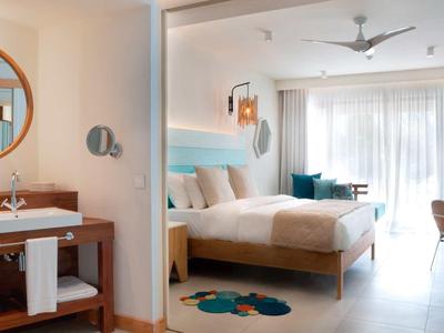 Moderní hotelový pokoj s manželskou postelí, posezením a otevřenou koupelnou se zrcadlem