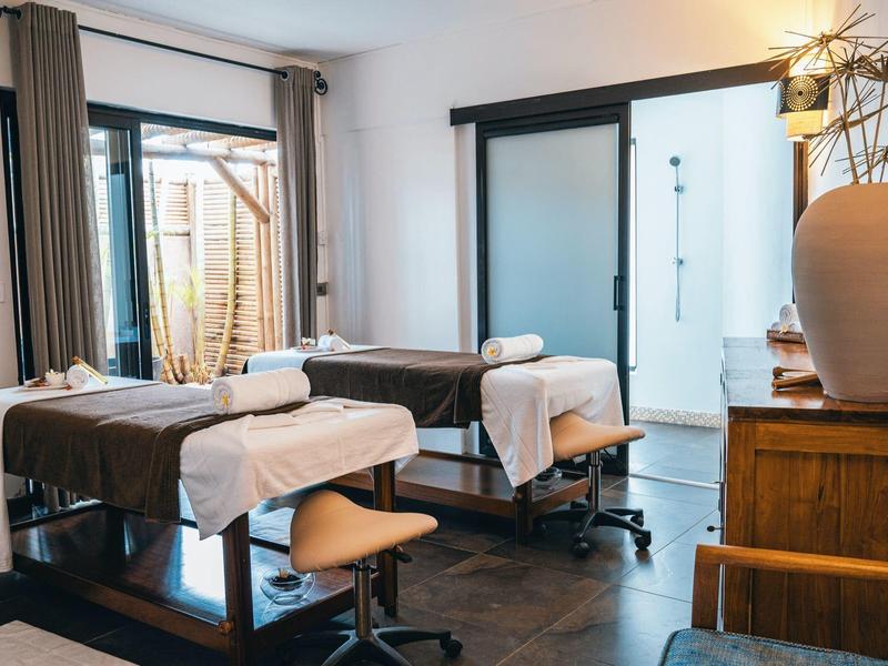 A bright treatment room with two massage beds and chairs in a wellness hotel.