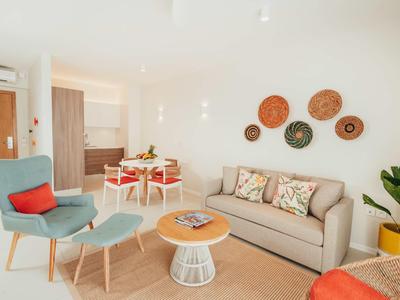 Soggiorno luminoso con divano grigio, poltrona blu e tavolo da pranzo con sedie bianche.