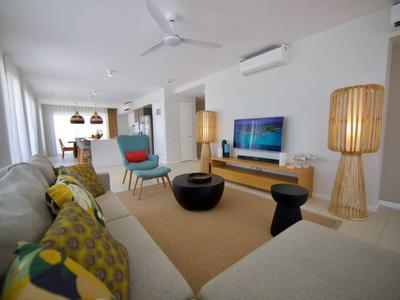 Soggiorno luminoso con mobili moderni, tappeto e ventilatori a soffitto in un appartamento vacanze.