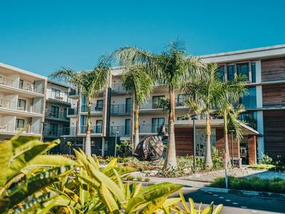 Hotel moderno con palme e giardino paesaggistico davanti sotto un cielo azzurro