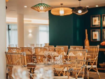 Sala da pranzo moderna con sedie in vimini e tavoli apparecchiati.