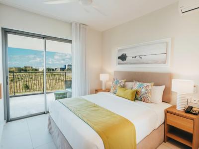 Camera luminosa e moderna con letto matrimoniale, comodini e accesso a un balcone con vista.