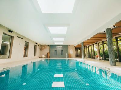 Interno di una piscina coperta luminosa e moderna con grandi finestre.