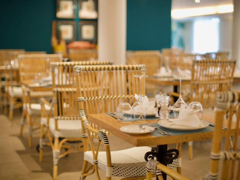 Accogliente area ristorazione dell'hotel con tavoli in legno e sedie in legno chiaro.