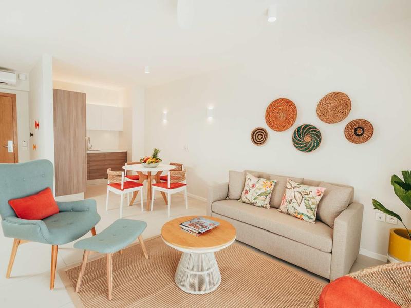 Soggiorno luminoso con poltrone comode, divano, decorazioni murali e piante in un hotel.