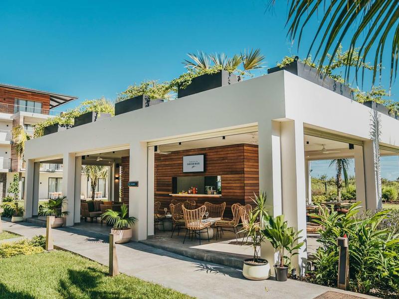 Lounge moderna all'aperto con colonne bianche e decorazioni in legno in un hotel tropicale.