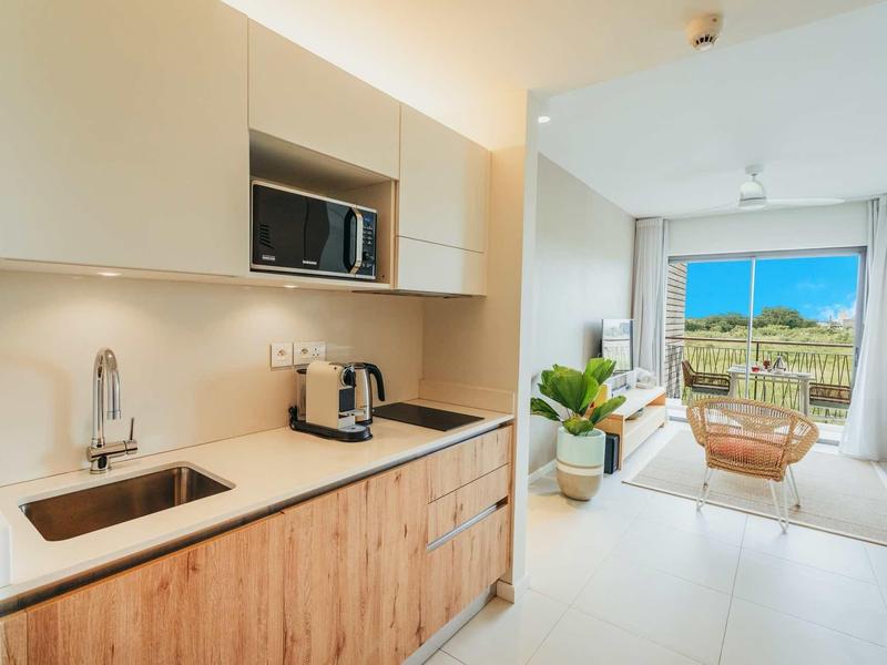Cucina moderna con armadi in legno e vista sulla terrazza con sedie e paesaggio verde.