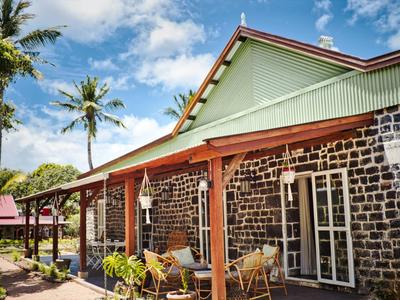 Ein Haus mit schwarz-weißen Steinwänden, rotem Holzrahmen und grüner Dachspitze bei blauem Himmel.